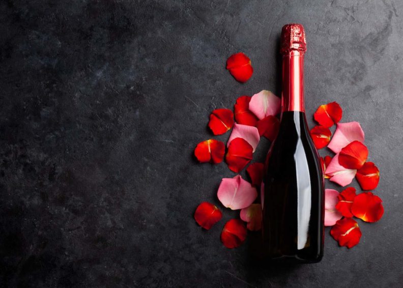 red bottle of champagne and rose petals